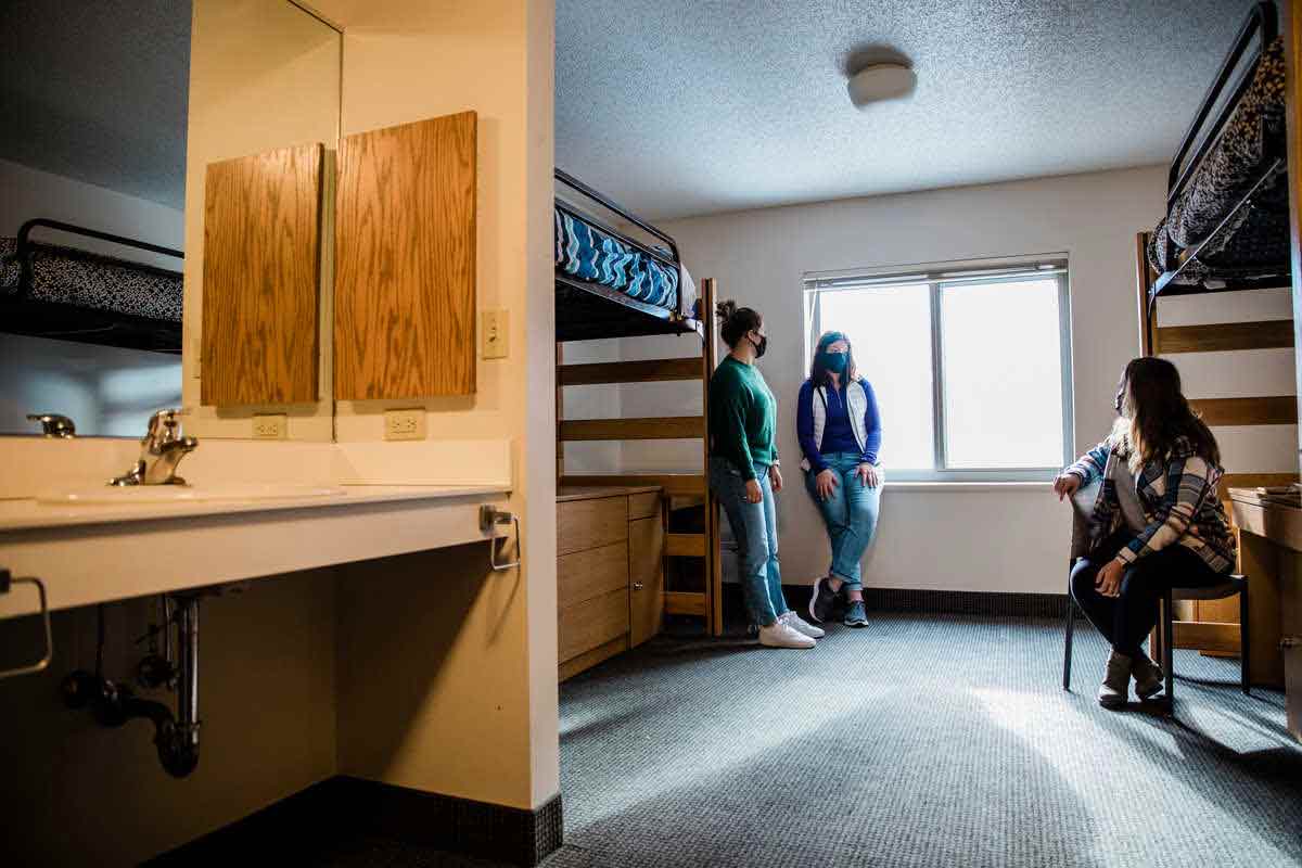 Flynn hall interior showing people in front of a lofted bed over a desk with a sink in the foreground