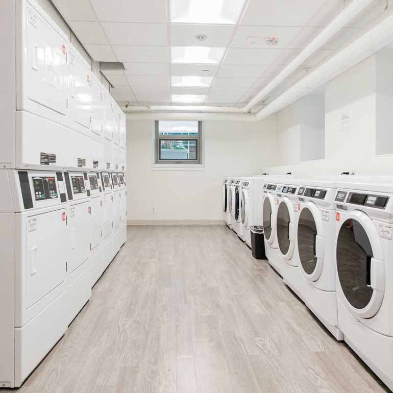 Laundry room with washers and dryers stacked.