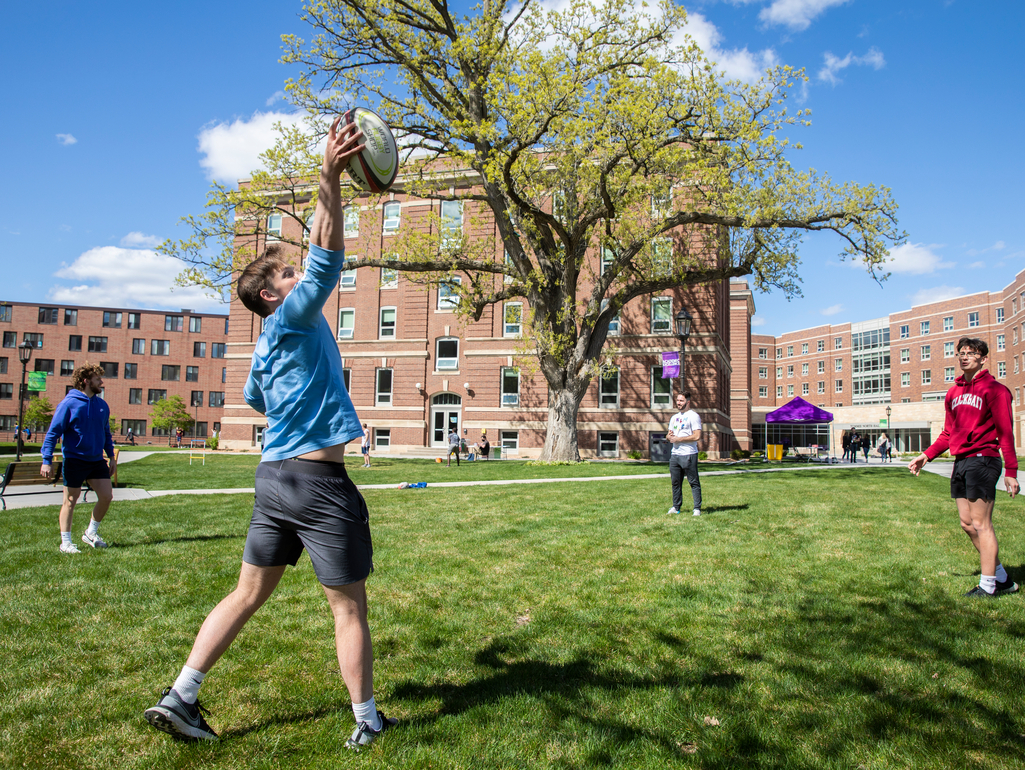 students toss around a rugby ball on campus