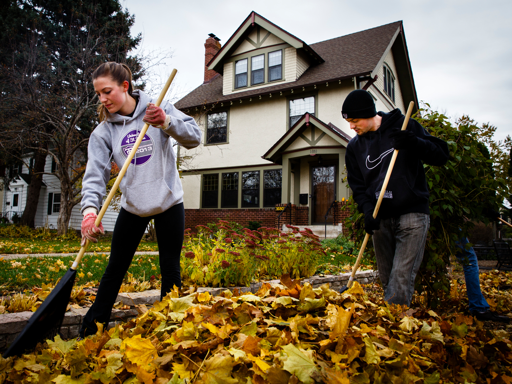 students raking leaves in front of a house