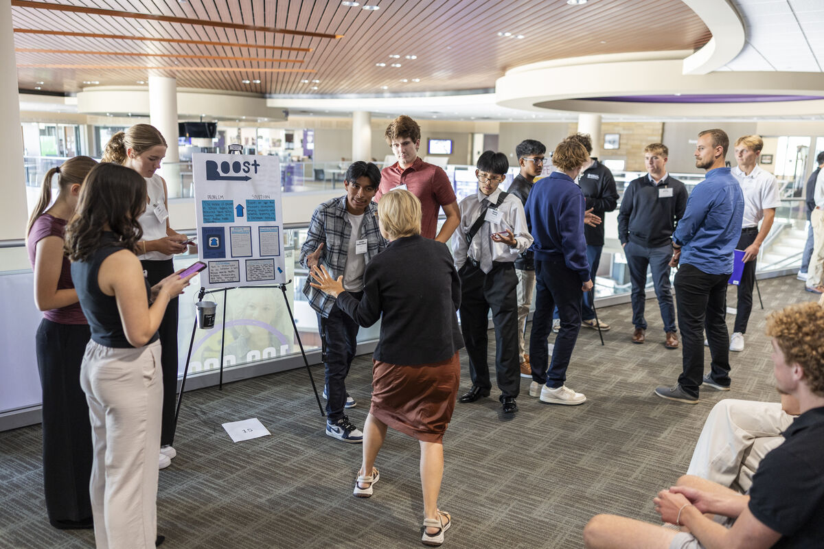 two students actively present a poster idea to a small group